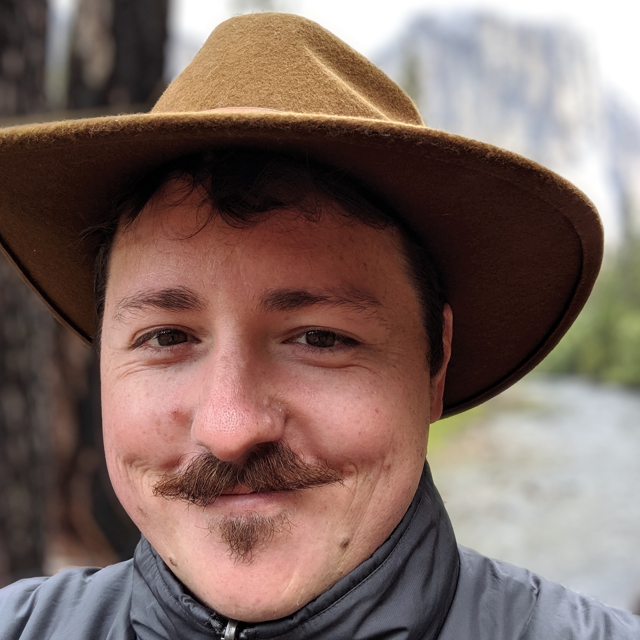 A photo of Kevin Kipp wearing a bandana around his neck, and a mustache on his face.